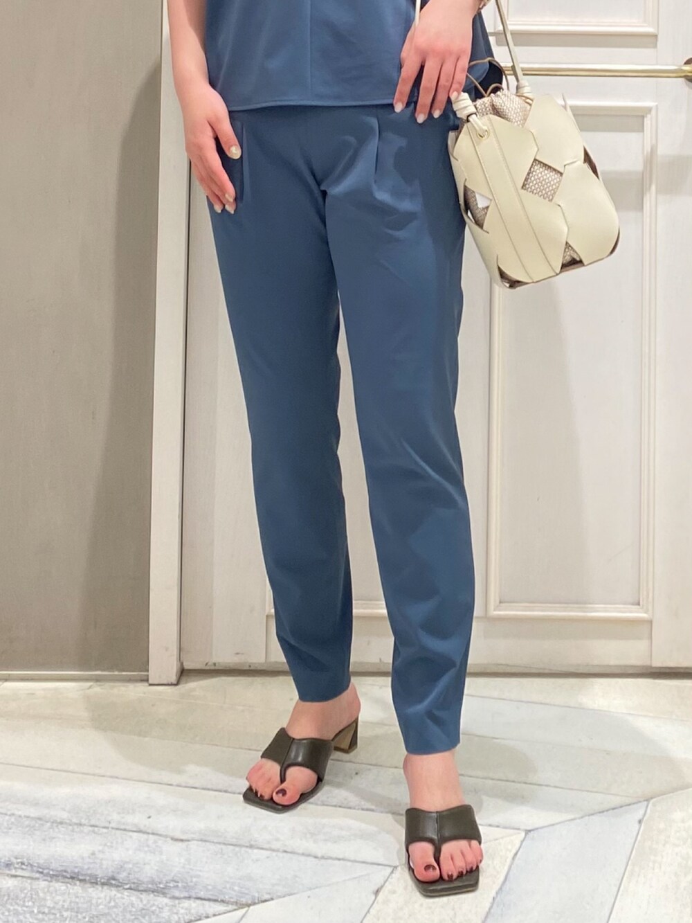 グリーン系のシャツ/ブラウス、ブラック系のスラックス、ホワイト系のショルダーバッグを着用したレディースの春コーディネートの2枚目の写真