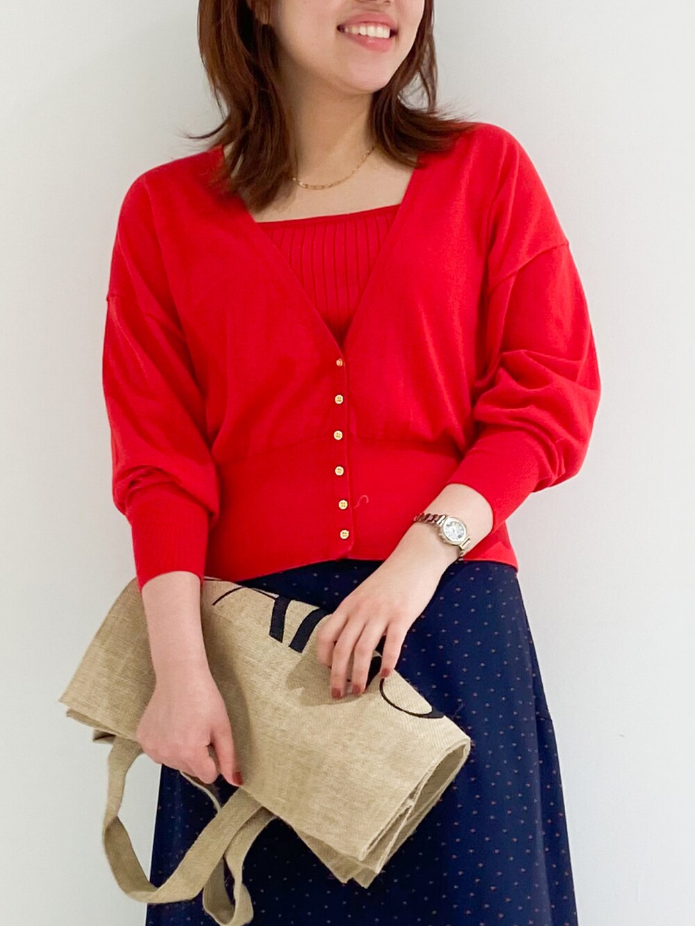 レッド系のカーディガン/ボレロ、ブルー系のスカート、ベージュ系のパンプスを着用したレディースの夏コーディネートの3枚目の写真