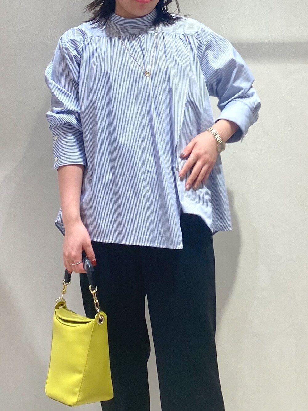 ブルー系のシャツ/ブラウス、ブルー系のハンドバッグ、ブラック系のスラックスを着用したレディースの秋コーディネートの5枚目の写真