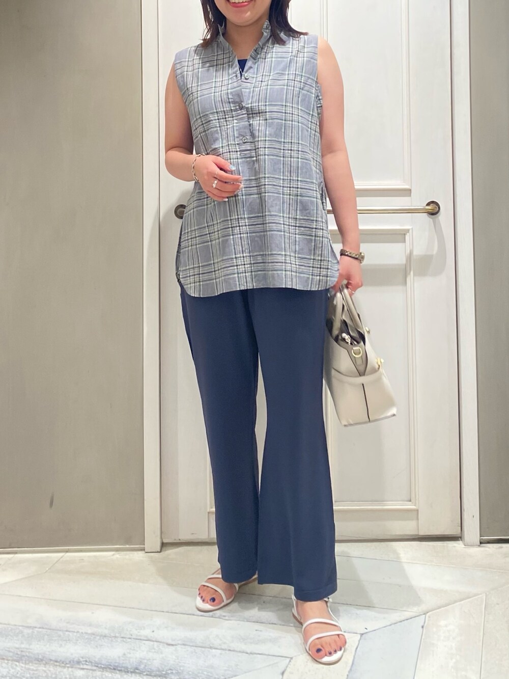 グリーン系のタンクトップ、レッド系のサンダル、ホワイト系のショルダーバッグを着用したレディースの夏コーディネートの2枚目の写真