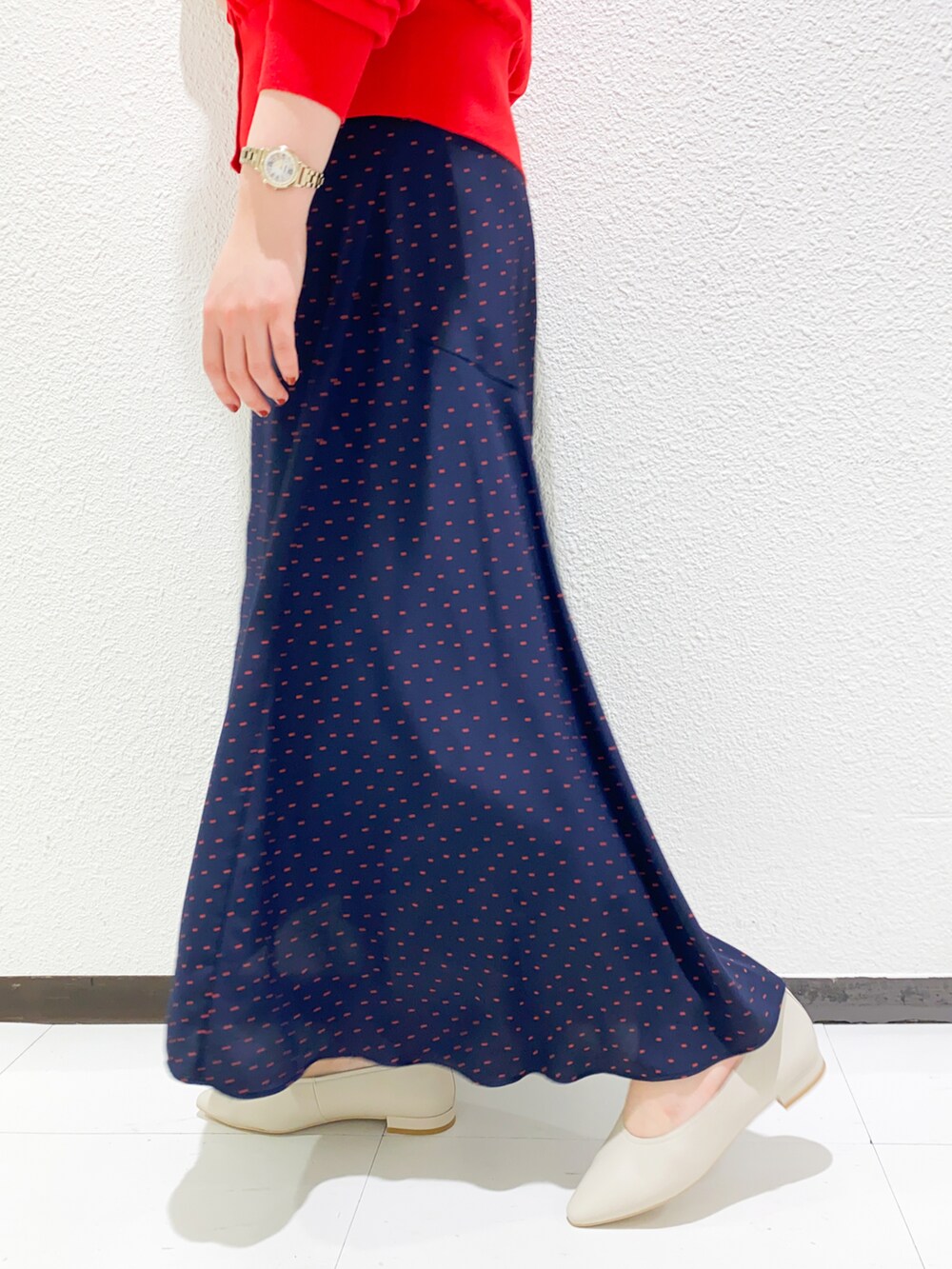 レッド系のカーディガン/ボレロ、ブルー系のスカート、ベージュ系のパンプスを着用したレディースの夏コーディネートの4枚目の写真