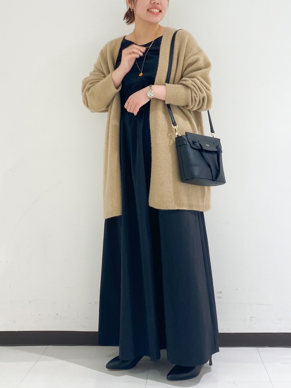 ベージュ系のカーディガン/ボレロ、ブラック系のワンピース/ドレス、ブラック系のブーツを着用したレディースの冬コーディネートの3枚目の写真