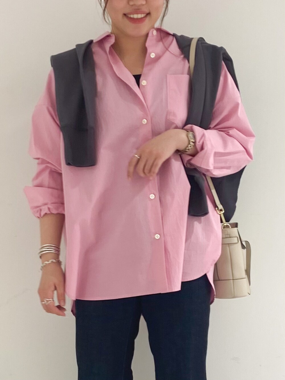 ホワイト系のショルダーバッグ、ブルー系のデニムパンツ、グレー系のパンプスを着用したレディースの春コーディネートの3枚目の写真