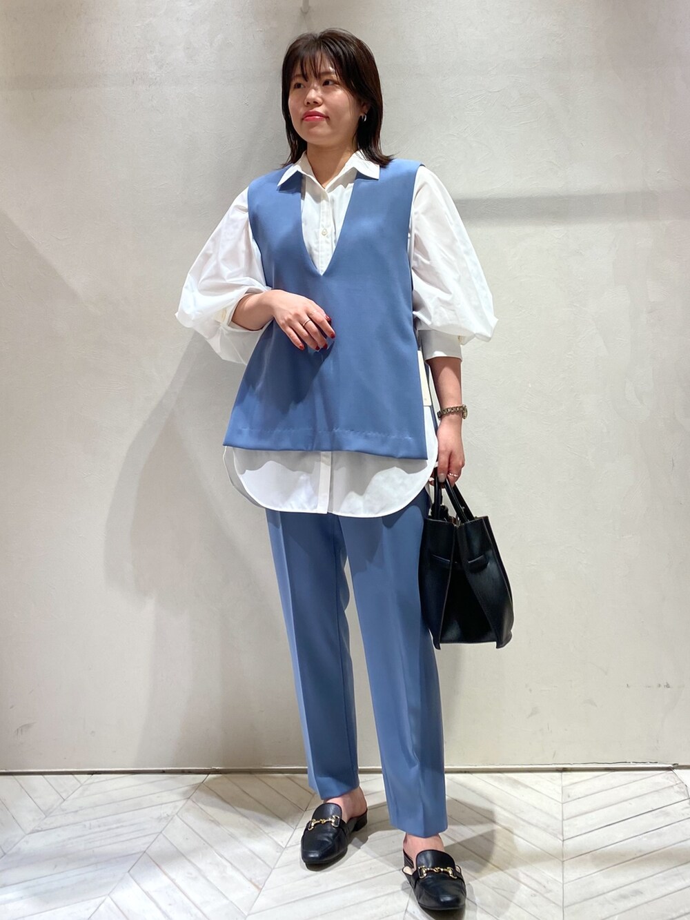 ホワイト系のシャツ/ブラウス、ブラック系のハンドバッグ、ブルー系のスラックスを着用したレディースの秋コーディネートの2枚目の写真