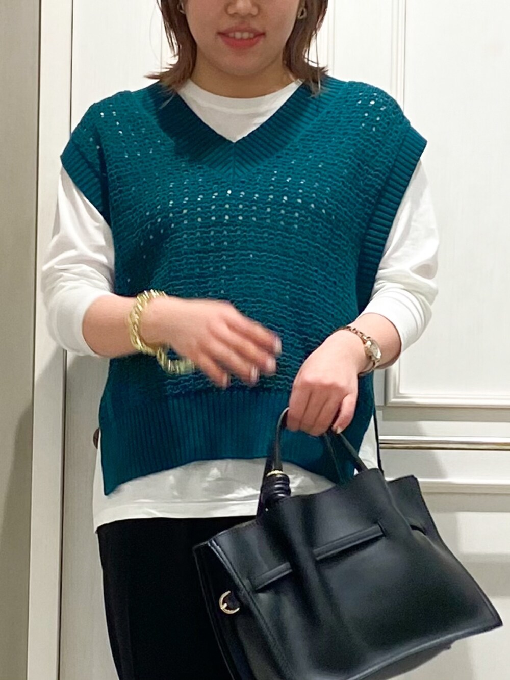 グリーン系のニット/セーター、ブラック系のサロペット/オーバーオール、ホワイト系のハンドバッグを着用したレディースの春コーディネートの4枚目の写真