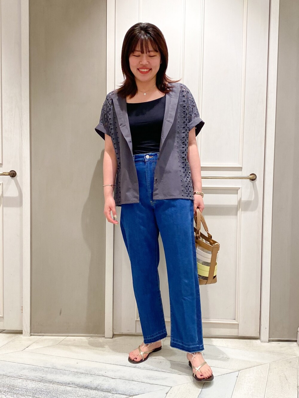 グレー系のシャツ/ブラウス、ブルー系のデニムパンツ、イエロー系のハンドバッグを着用したレディースの夏コーディネートの2枚目の写真