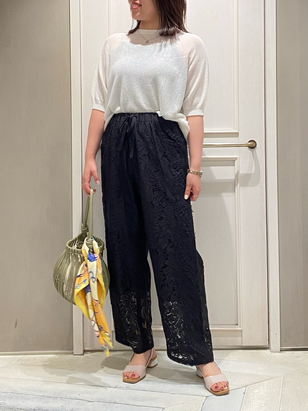 ホワイト系のニット/セーター、ブラック系のその他パンツ、グリーン系のショルダーバッグを着用したレディースの夏コーディネートの2枚目の写真