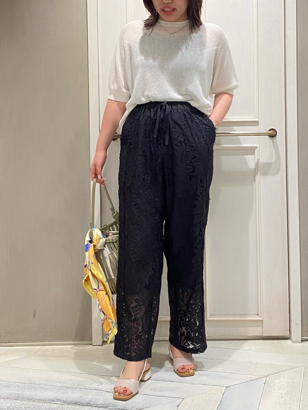 ホワイト系のニット/セーター、ブラック系のその他パンツ、グリーン系のショルダーバッグを着用したレディースの夏コーディネートの4枚目の写真