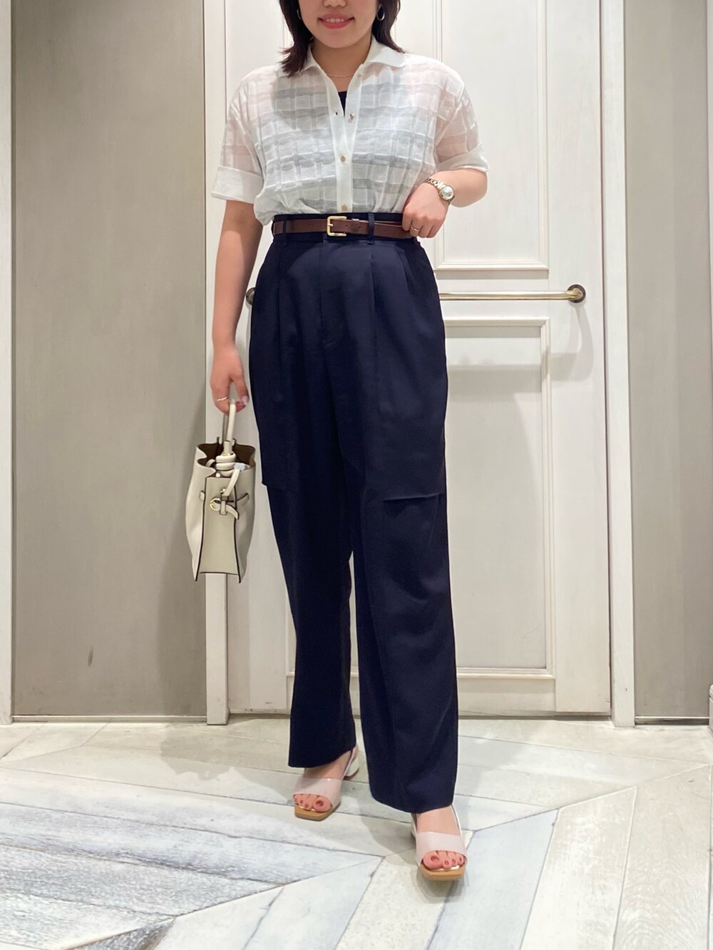 グリーン系のトートバッグ、ホワイト系のサンダル、ホワイト系のニット/セーターを着用したレディースの夏コーディネートの2枚目の写真