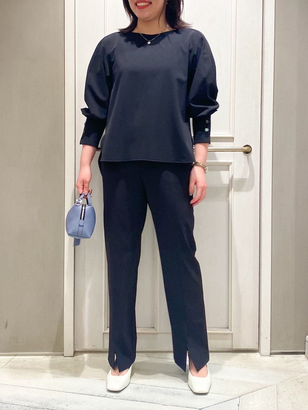 ブラック系のシャツ/ブラウス、ブラック系のスラックス、ブルー系のハンドバッグを着用したレディースの春コーディネートの5枚目の写真