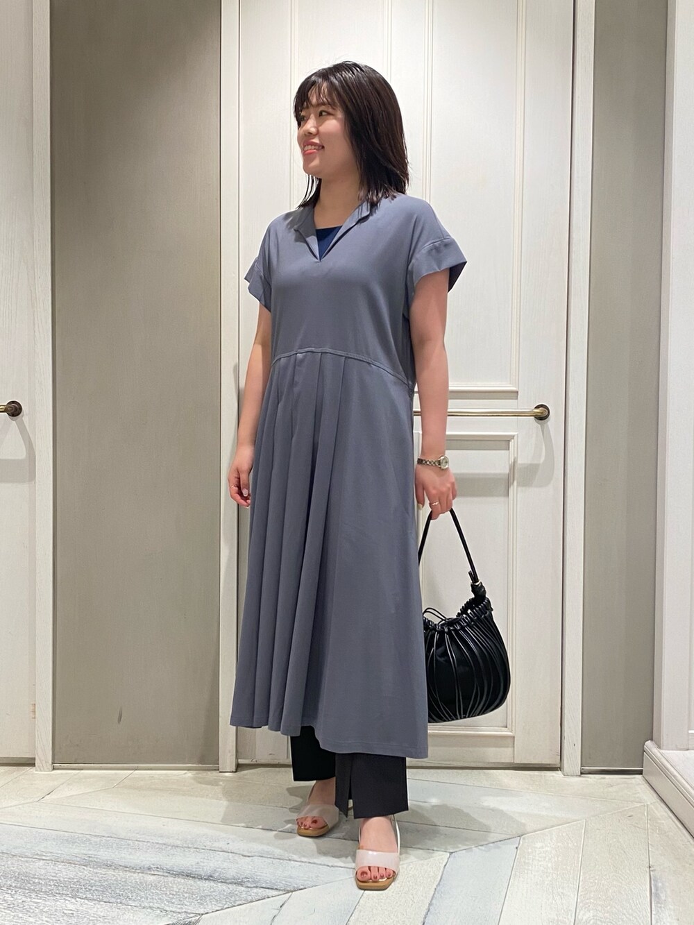 グレー系のワンピース、ホワイト系のサンダル、グレー系のスラックスを着用したレディースの夏コーディネートの2枚目の写真