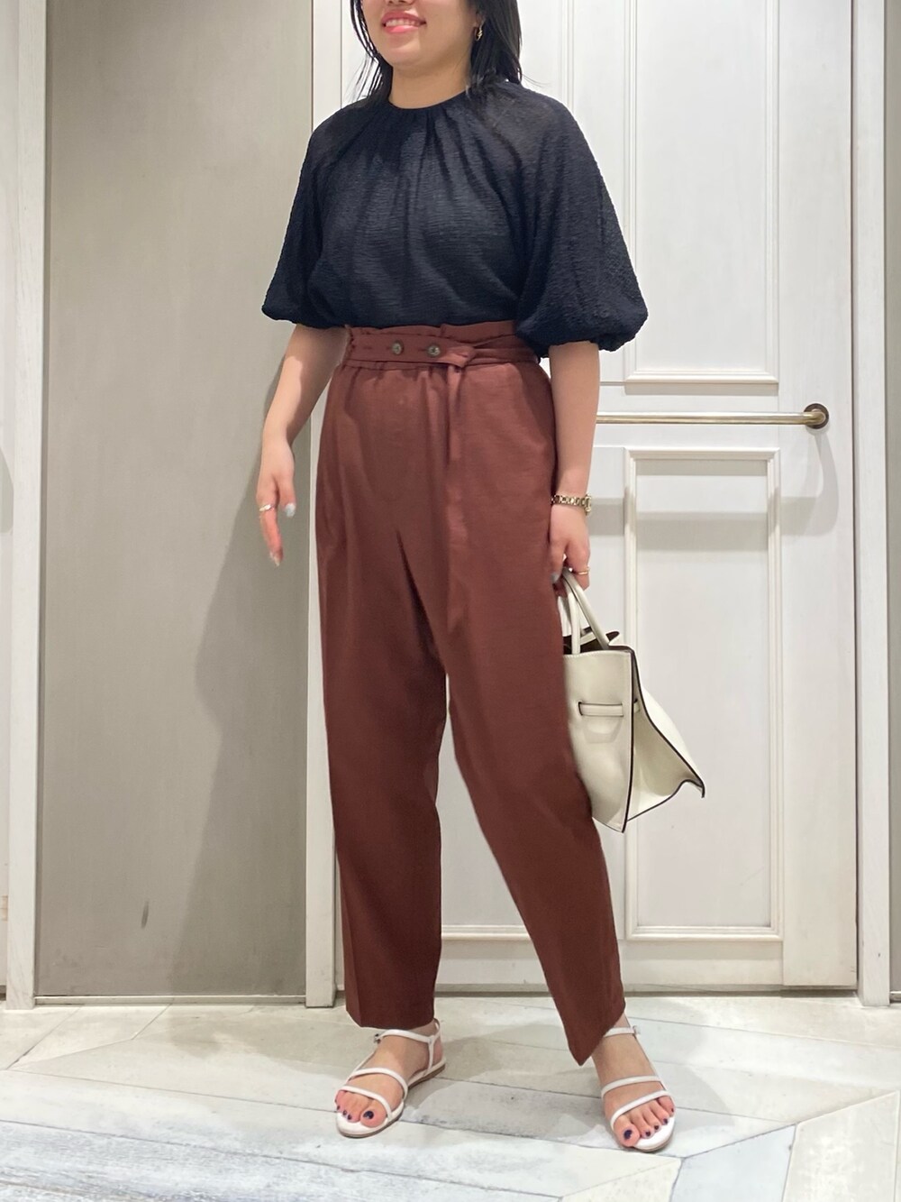 ブラック系のシャツ/ブラウス、レッド系のスラックス、ホワイト系のハンドバッグを着用したレディースの夏コーディネートの2枚目の写真