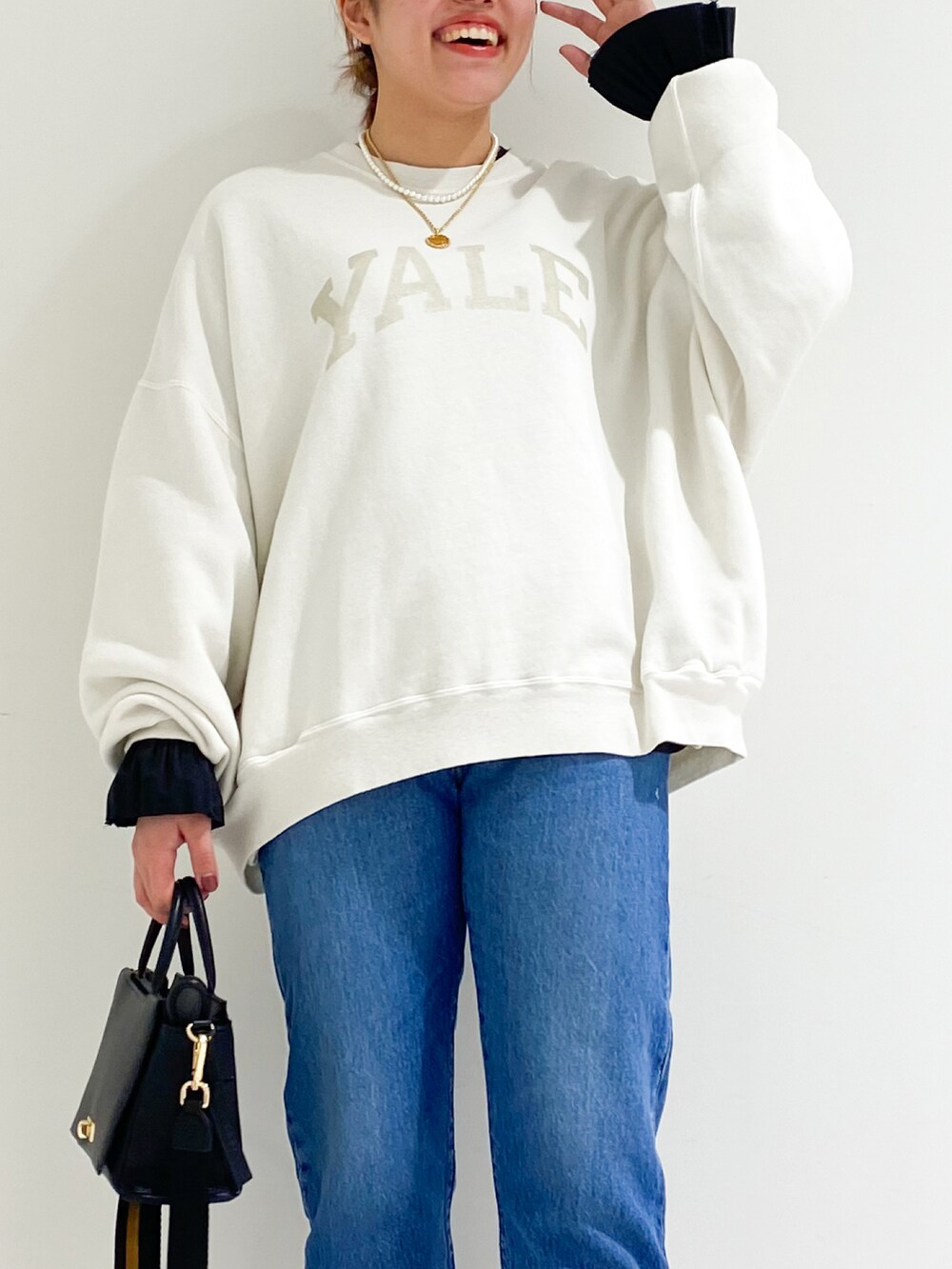 ホワイト系のスウェット、ブラウン系のハンドバッグ、ブラック系のパンプスを着用したレディースの秋コーディネートの4枚目の写真