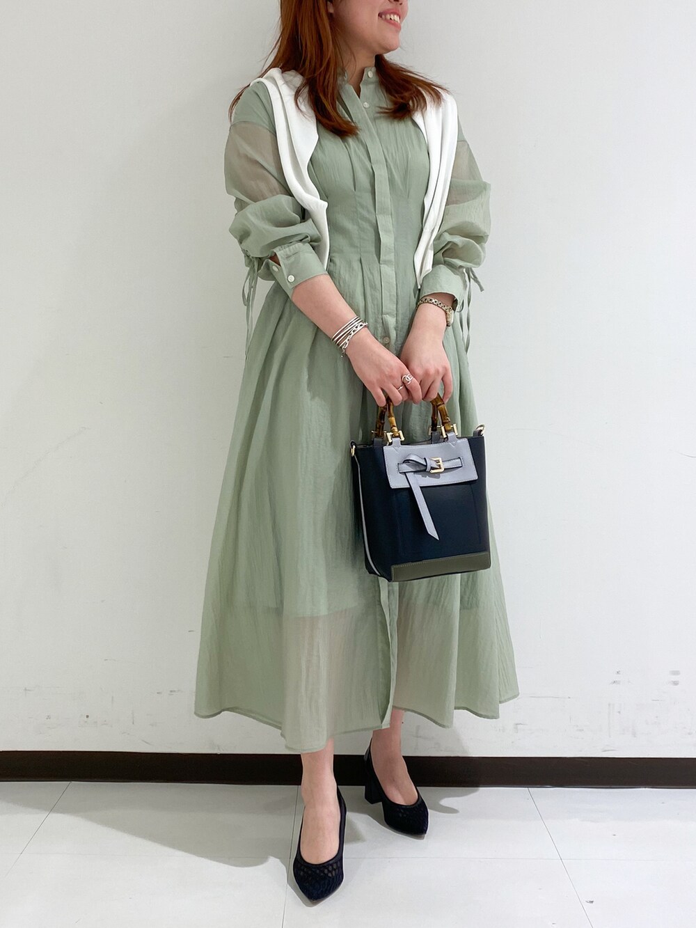 ホワイト系のカーディガン/ボレロ、グリーン系のワンピース、ブラック系のトートバッグを着用したレディースの春コーディネートの2枚目の写真