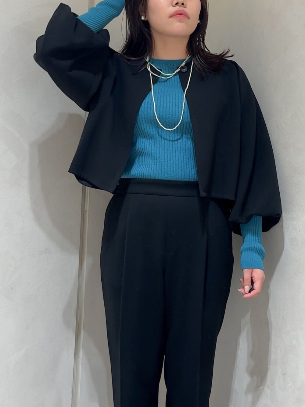 ブラック系のテーラードジャケット、ブルー系のニット/セーター、ブラック系のスラックスを着用したレディースの秋コーディネートの5枚目の写真