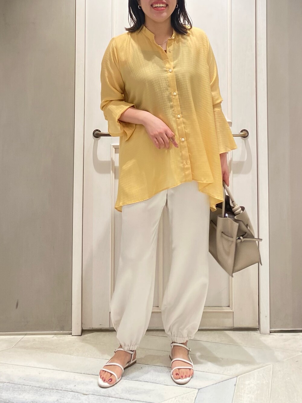 イエロー系のシャツ/ブラウス、ホワイト系のその他パンツ、ベージュ系のハンドバッグを着用したレディースの夏コーディネートの5枚目の写真