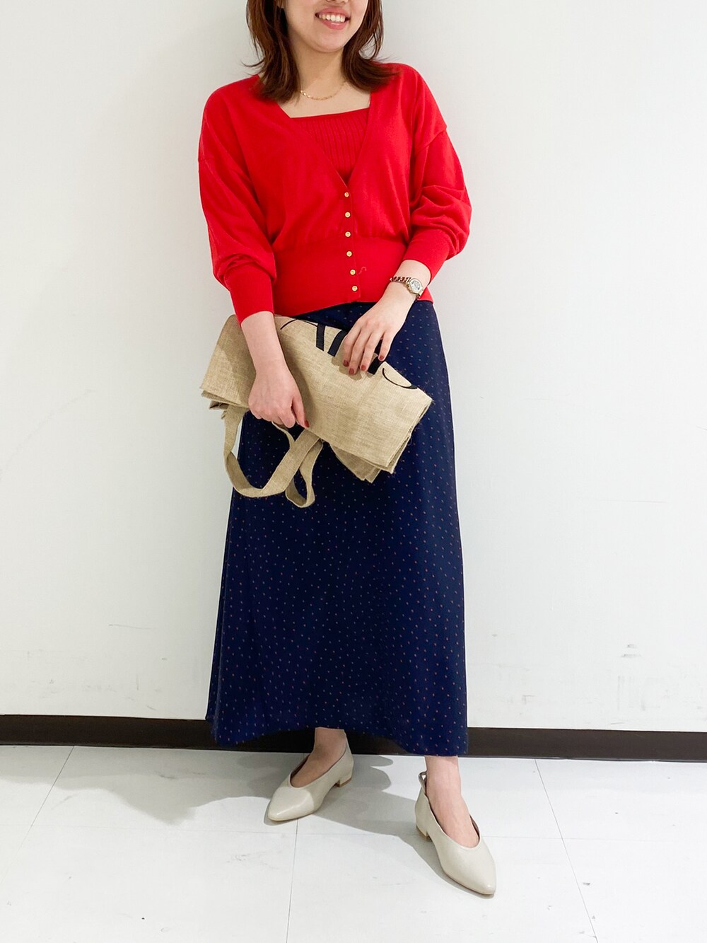 レッド系のカーディガン/ボレロ、ブルー系のスカート、ベージュ系のパンプスを着用したレディースの夏コーディネートの2枚目の写真