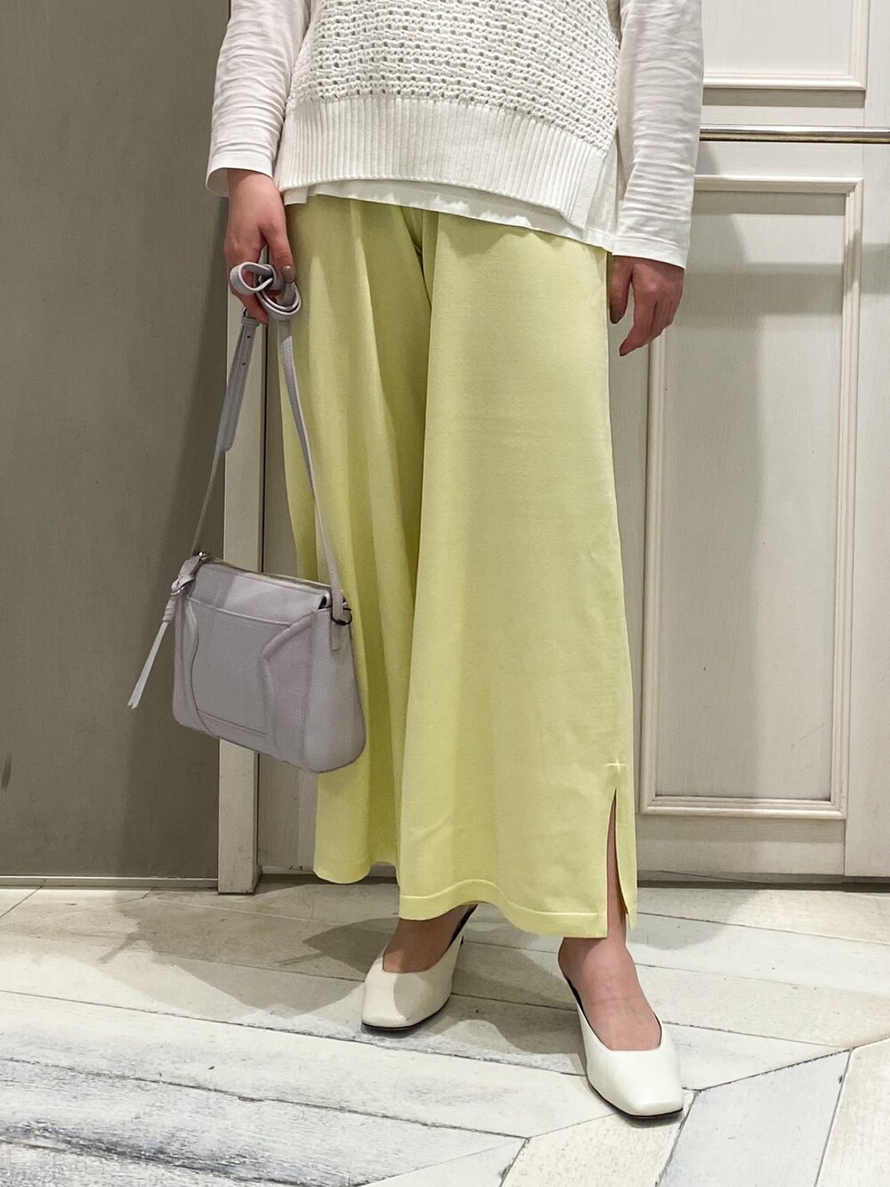 グリーン系のニット/セーター、イエロー系のその他パンツ、パープル系のショルダーバッグを着用したレディースの春コーディネートの2枚目の写真