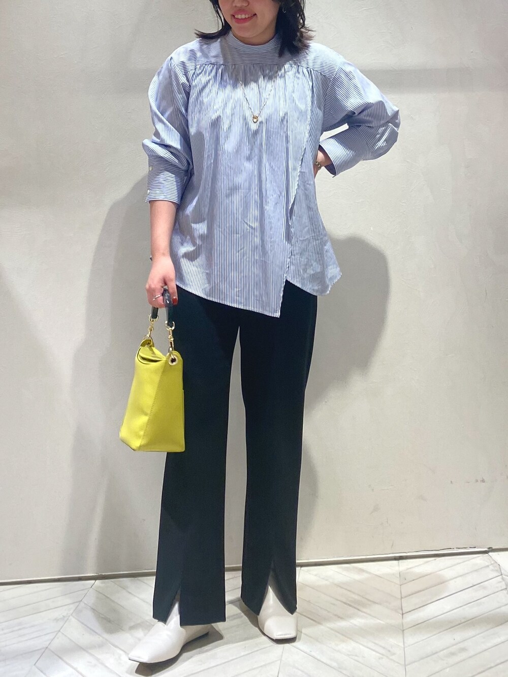 ブルー系のシャツ/ブラウス、ブルー系のハンドバッグ、ブラック系のスラックスを着用したレディースの秋コーディネートの3枚目の写真
