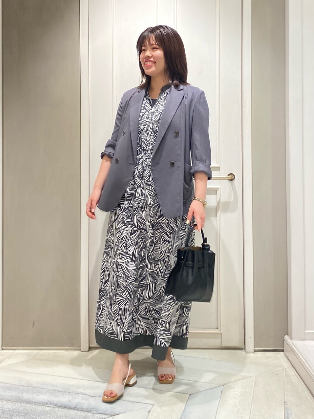 グレー系のワンピース、グレー系のテーラードジャケット、グリーン系のトートバッグを着用したレディースの夏コーディネートの3枚目の写真
