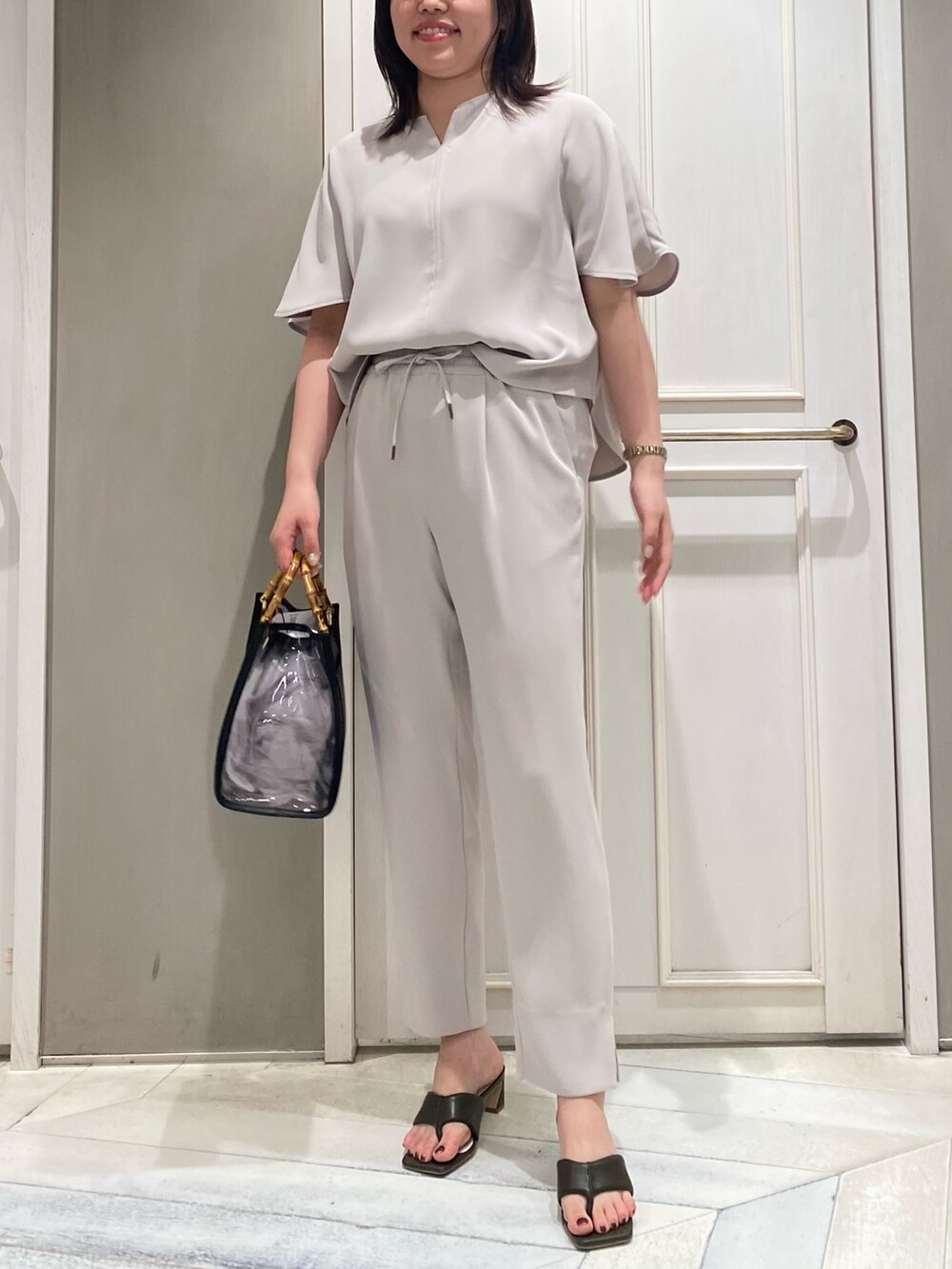 ブラック系のスラックス、ブラック系のトートバッグ、グリーン系のサンダルを着用したレディースの春コーディネートの3枚目の写真