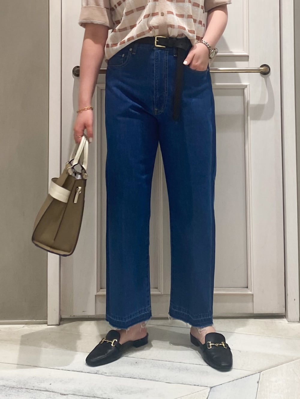 ベージュ系のニット/セーター、ベージュ系のショルダーバッグ、ブルー系のデニムパンツを着用したレディースの春コーディネートの4枚目の写真