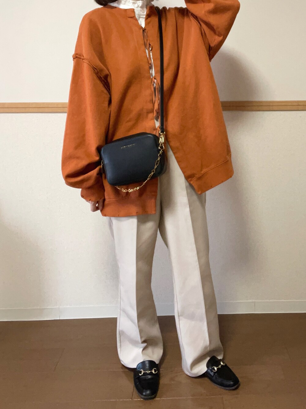 オレンジ系のスウェット、ホワイト系のシャツ/ブラウス、ホワイト系のスラックスを着用したレディースの秋コーディネートの3枚目の写真