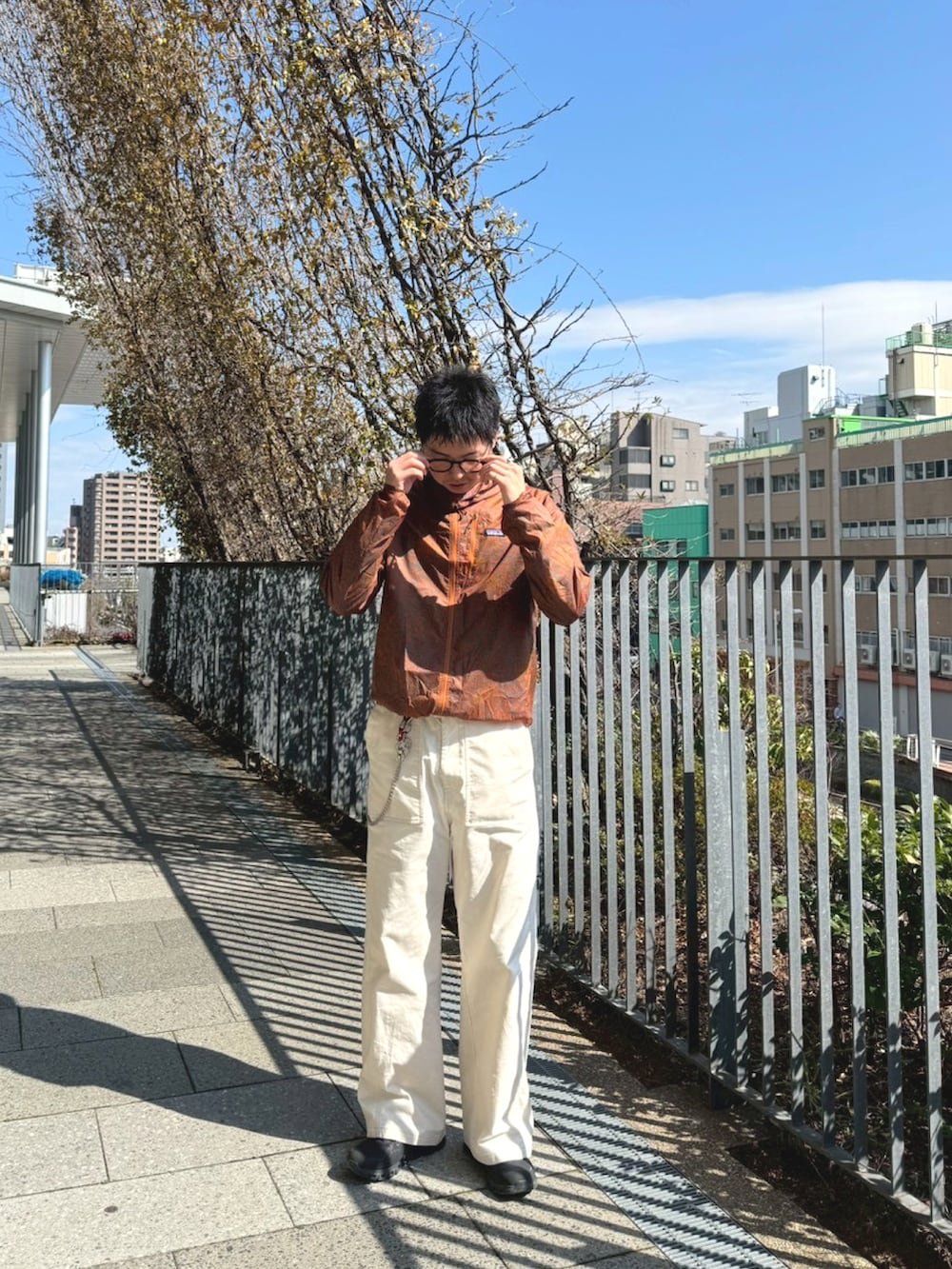 ホワイト系のチノパンツ、ブラック系のスニーカー、ブラウン系のジャケット/アウターを着用したメンズの春コーディネートの2枚目の写真