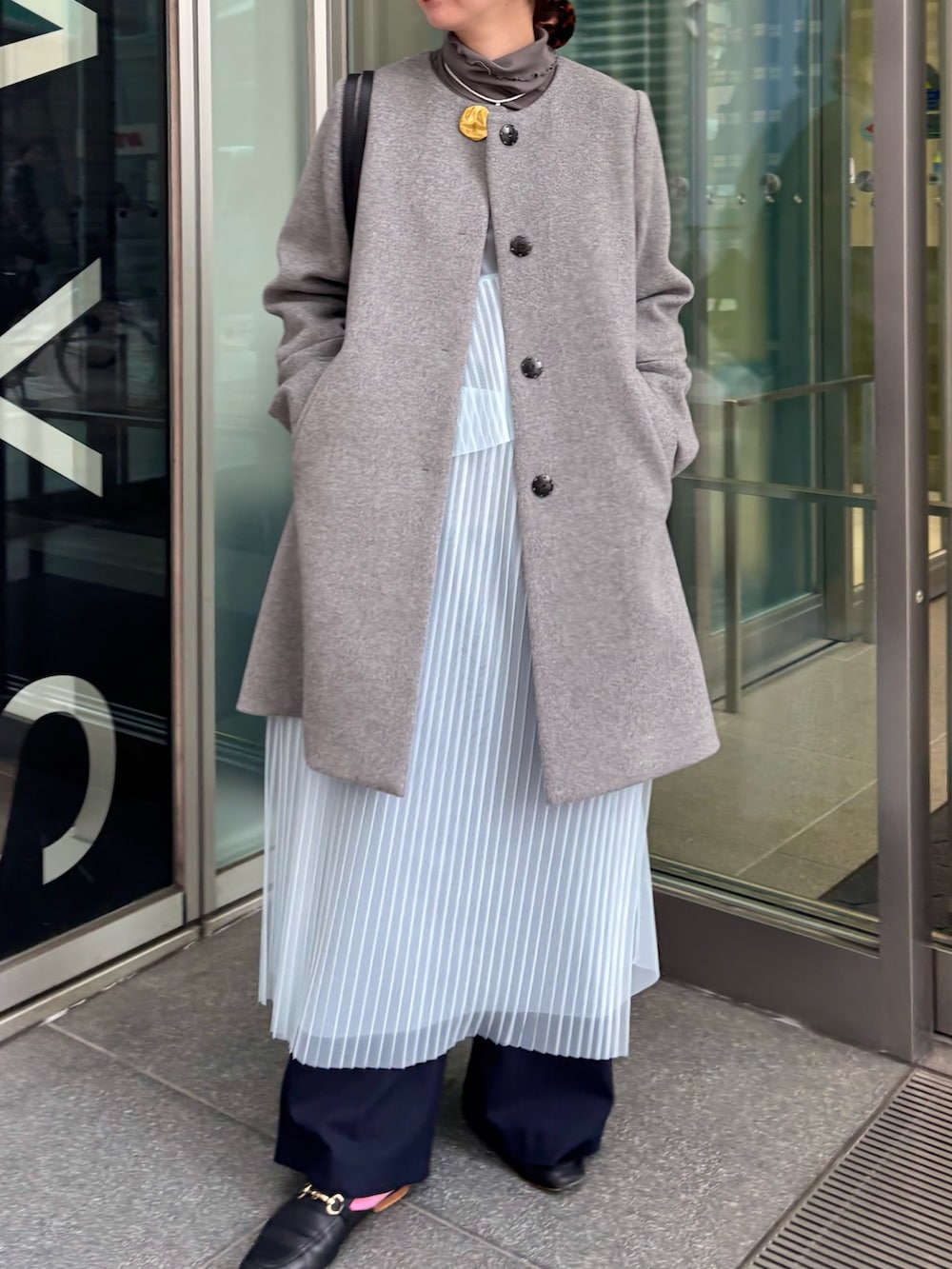 グレー系のノーカラーコート、グレー系のTシャツ/カットソー、ブルー系のワンピースを着用したレディースの冬コーディネートの6枚目の写真