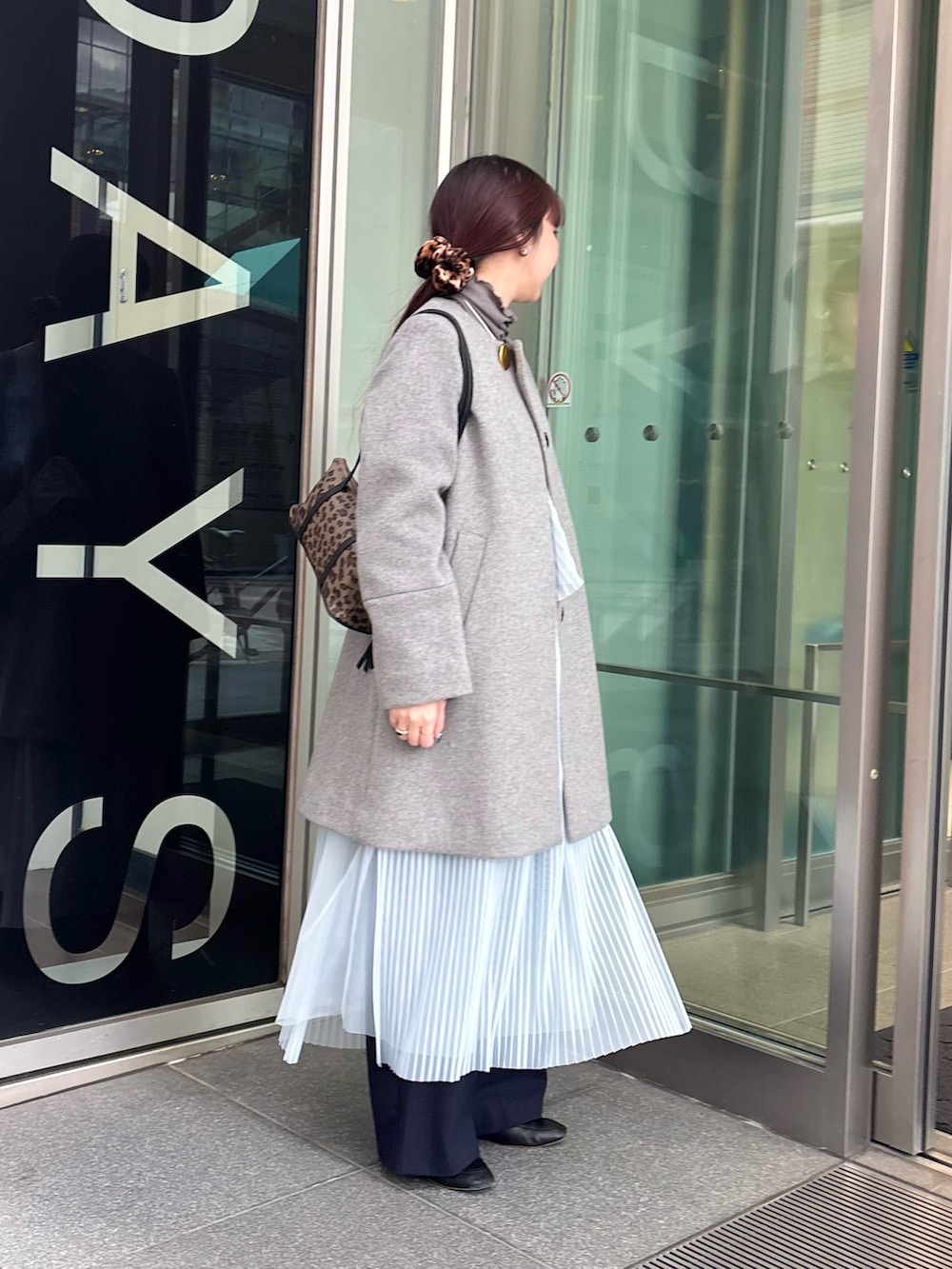 グレー系のノーカラーコート、グレー系のTシャツ/カットソー、ブルー系のワンピースを着用したレディースの冬コーディネートの2枚目の写真