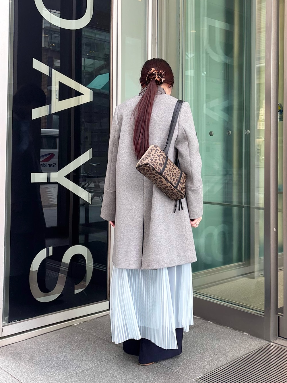 グレー系のノーカラーコート、グレー系のTシャツ/カットソー、ブルー系のワンピースを着用したレディースの冬コーディネートの3枚目の写真