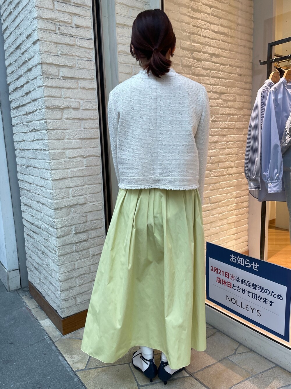 ホワイト系のノーカラージャケット、イエロー系のスカート、ブルー系のサンダルを着用したレディースの冬コーディネートの3枚目の写真