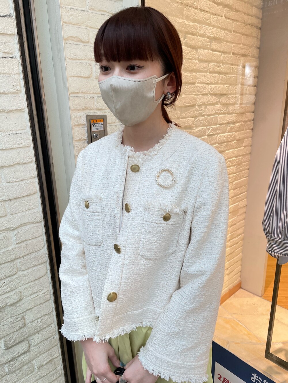 ホワイト系のノーカラージャケット、イエロー系のスカート、ブルー系のサンダルを着用したレディースの冬コーディネートの4枚目の写真