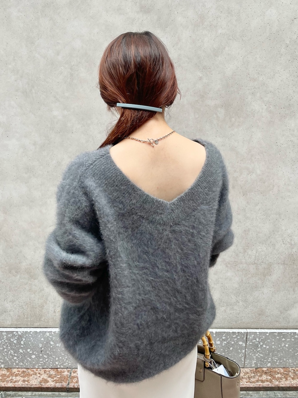 グレー系のニット/セーター、ホワイト系のスカート、ベージュ系のショルダーバッグを着用したレディースの秋コーディネートの3枚目の写真