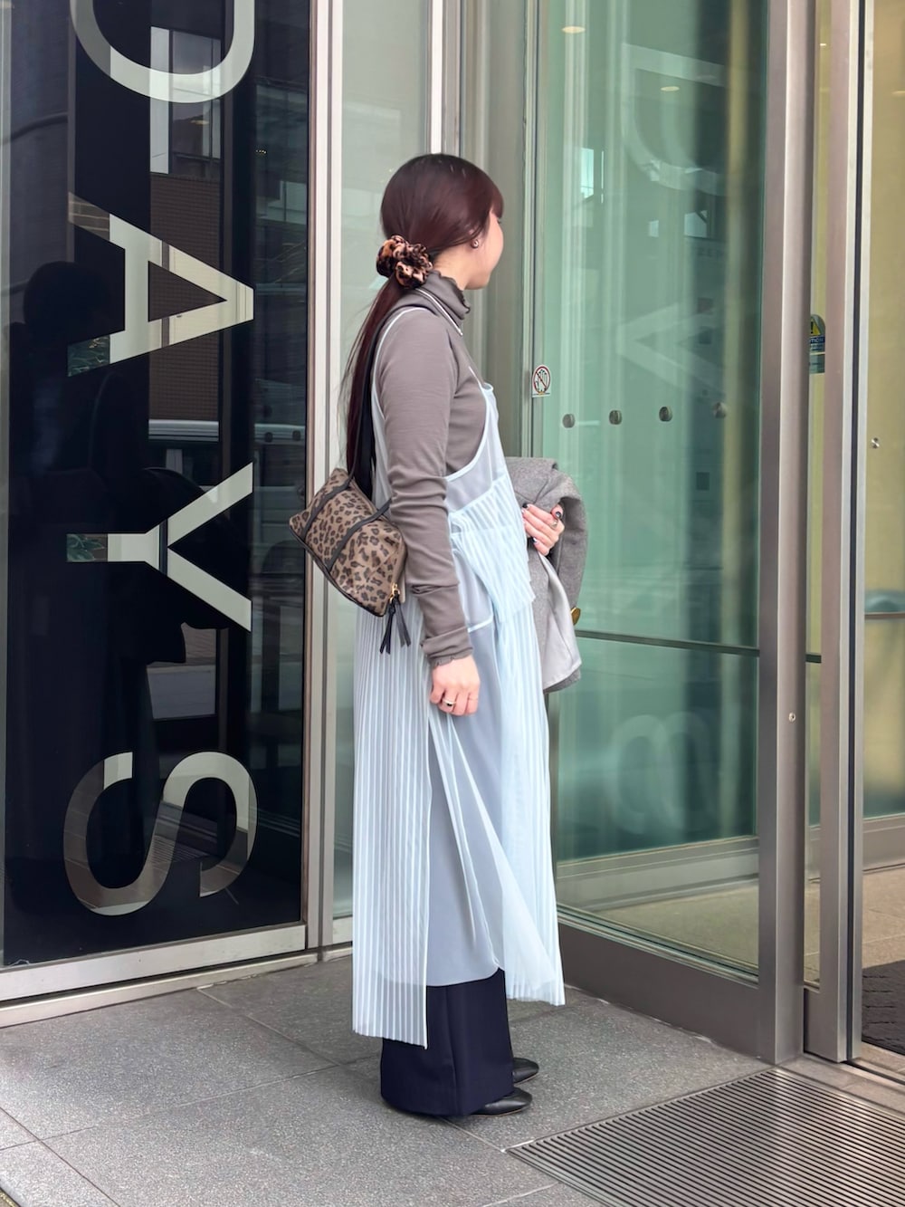 グレー系のノーカラーコート、グレー系のTシャツ/カットソー、ブルー系のワンピースを着用したレディースの冬コーディネートの5枚目の写真