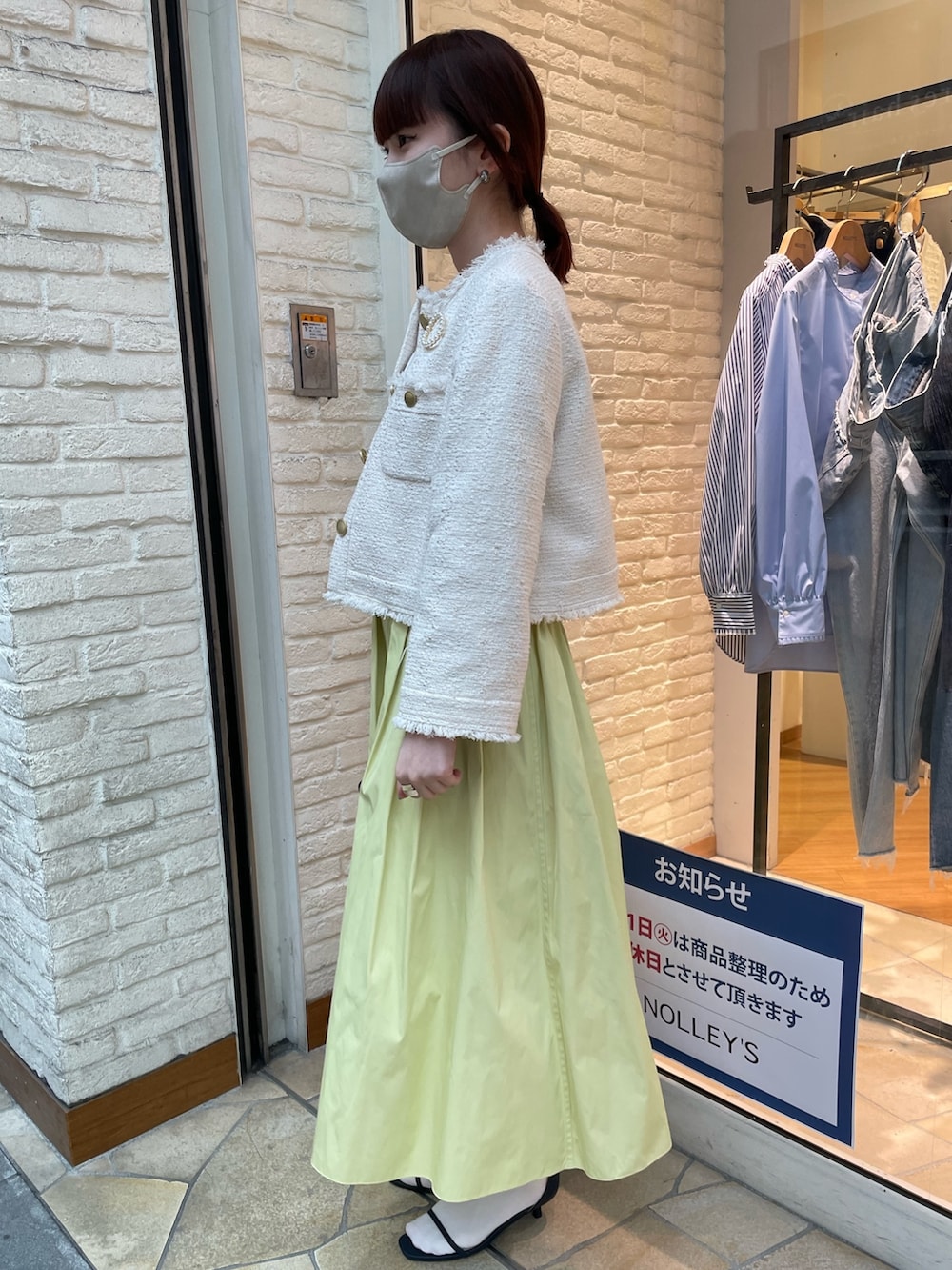 ホワイト系のノーカラージャケット、イエロー系のスカート、ブルー系のサンダルを着用したレディースの冬コーディネートの2枚目の写真