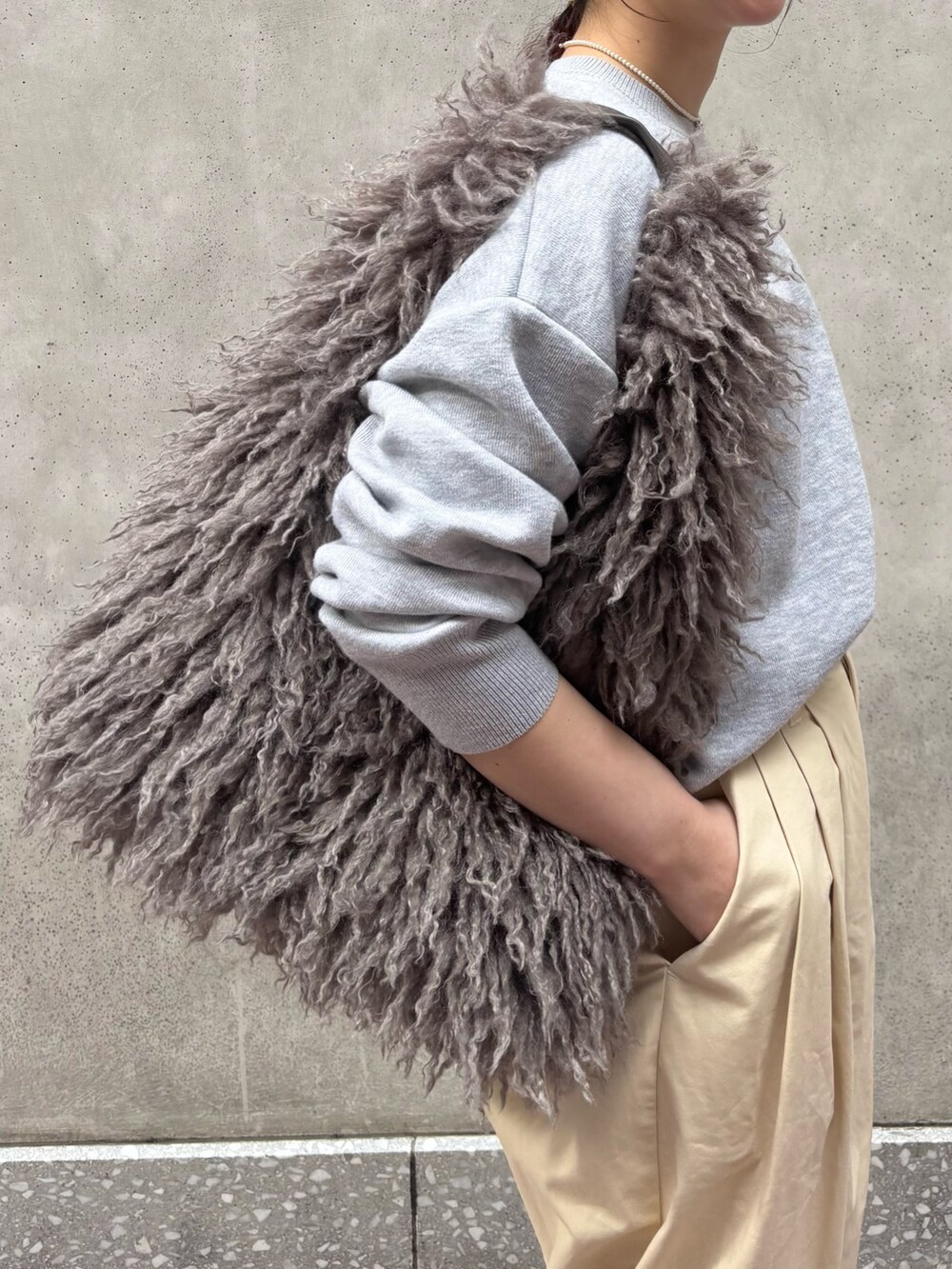 グレー系のニット/セーター、ホワイト系のその他パンツ、ベージュ系のショルダーバッグを着用したレディースの秋コーディネートの3枚目の写真