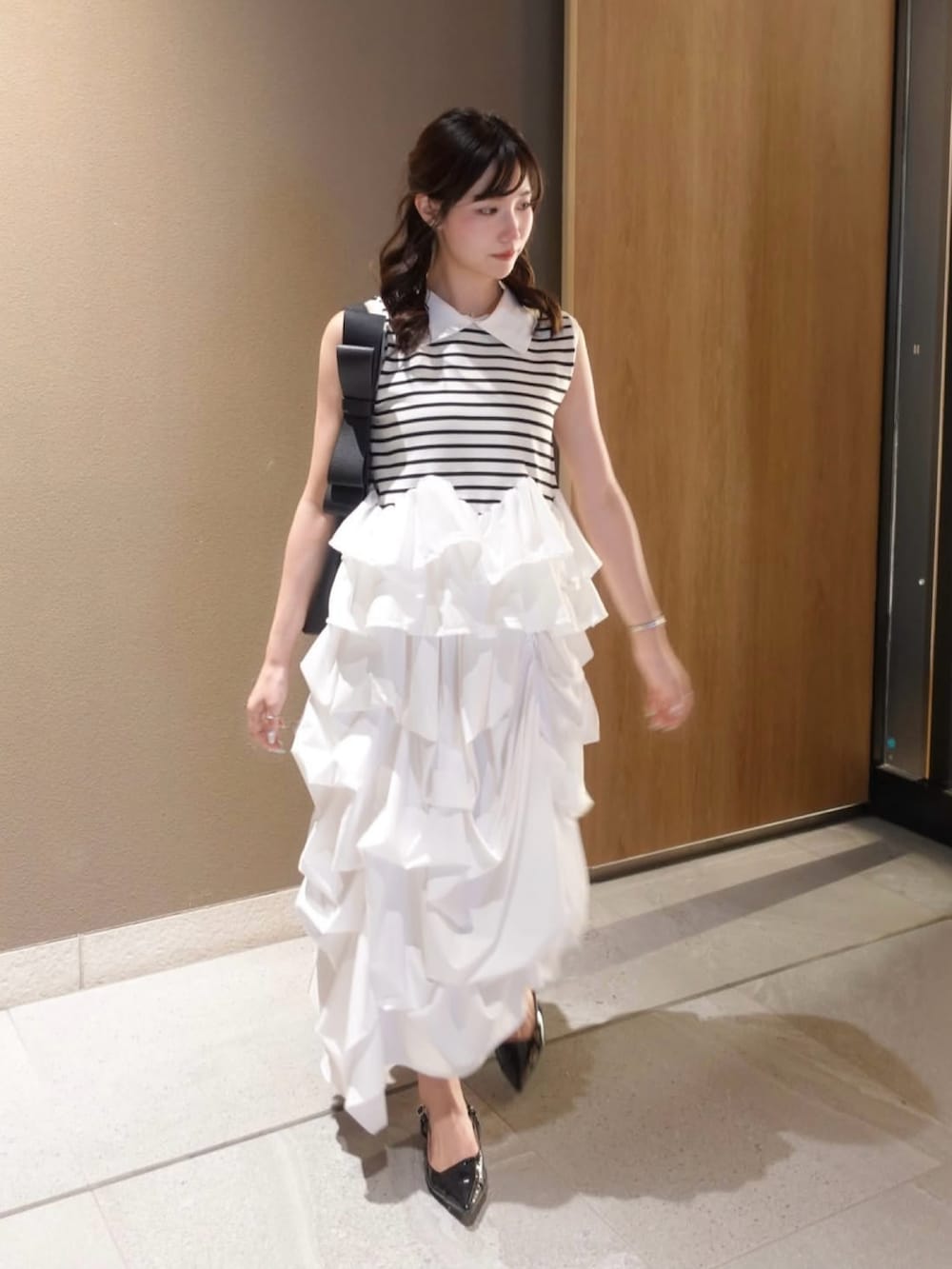 ホワイト系のスカート、ブラック系のショルダーバッグ、その他のシャツ/ブラウスを着用したレディースの夏コーディネートの2枚目の写真