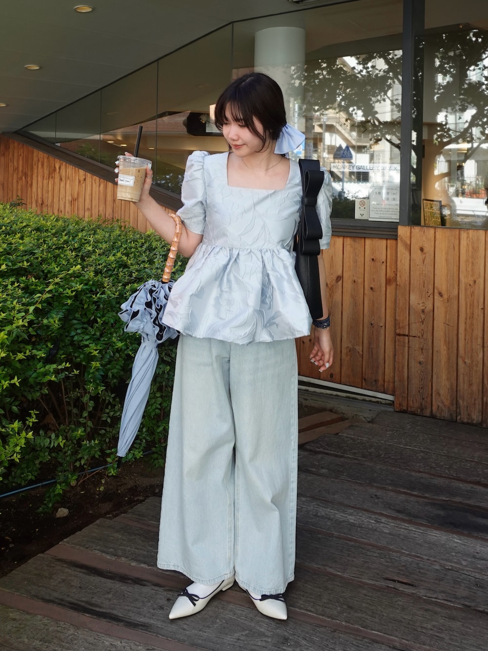 ブラック系のシャツ/ブラウス、ブラック系のショルダーバッグ、ブルー系のデニムパンツを着用したレディースの春コーディネートの2枚目の写真