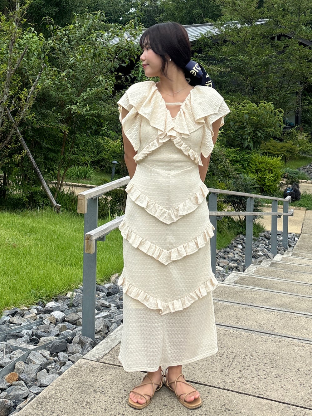 イエロー系のワンピース、ホワイト系のハンドバッグ、ベージュ系のサンダルを着用したレディースの夏コーディネートの2枚目の写真