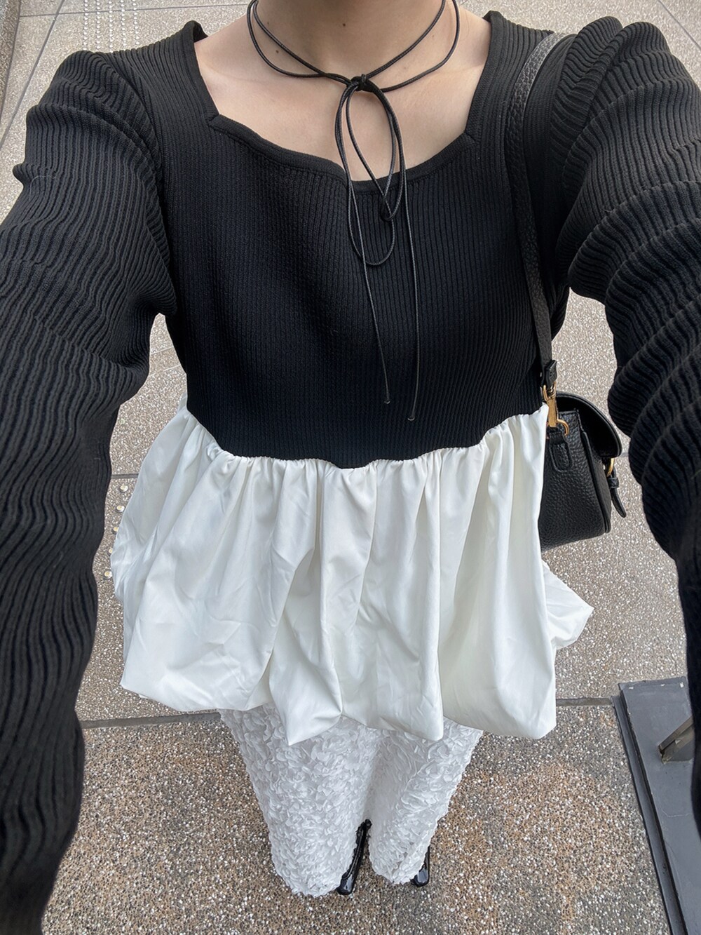 ブラック系のニット/セーター、ホワイト系のスカート、ブラック系のショルダーバッグを着用したレディースの秋コーディネートの2枚目の写真