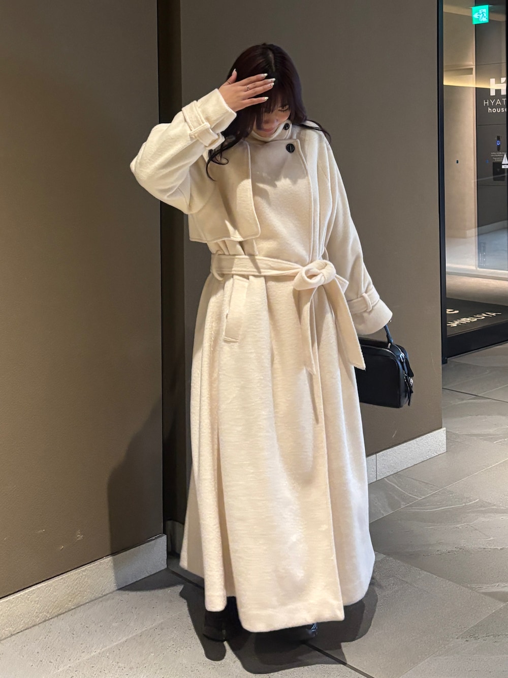 ホワイト系のステンカラーコート、ブラック系のボストンバッグ、ブラウン系のローファーを着用したレディースの冬コーディネートの2枚目の写真