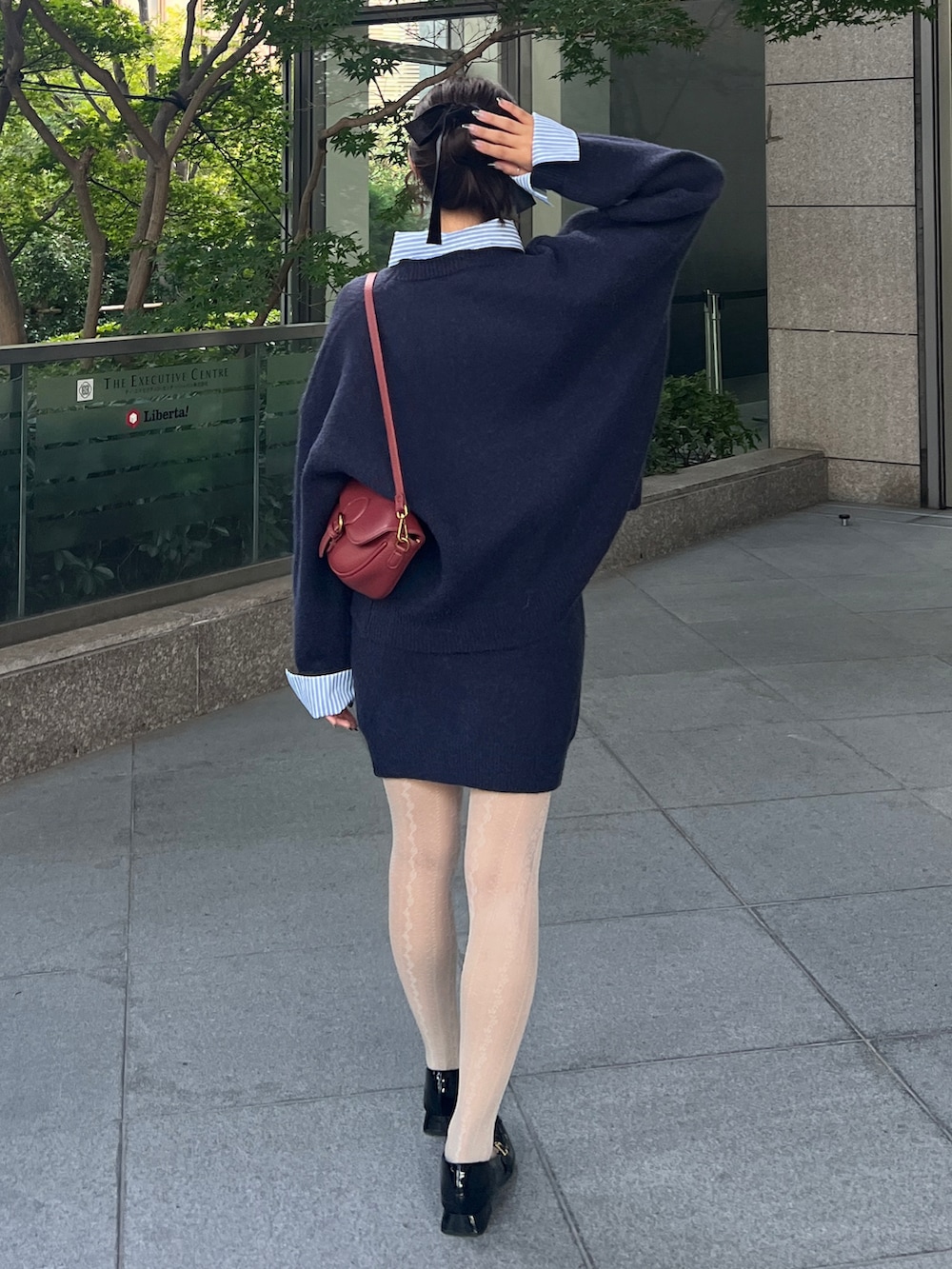 ブルー系のニット/セーター、ブルー系のスカート、レッド系のショルダーバッグを着用したレディースの秋コーディネートの2枚目の写真