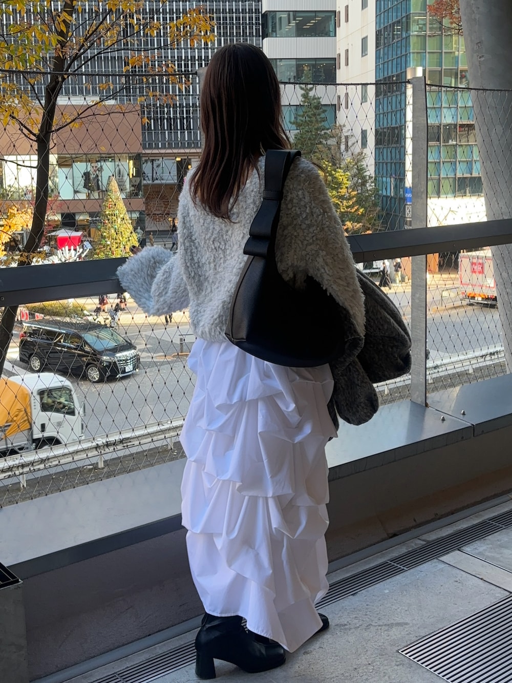 ホワイト系のスカート、ブラック系のショルダーバッグ、グレー系のニット/セーターを着用したレディースの冬コーディネートの3枚目の写真