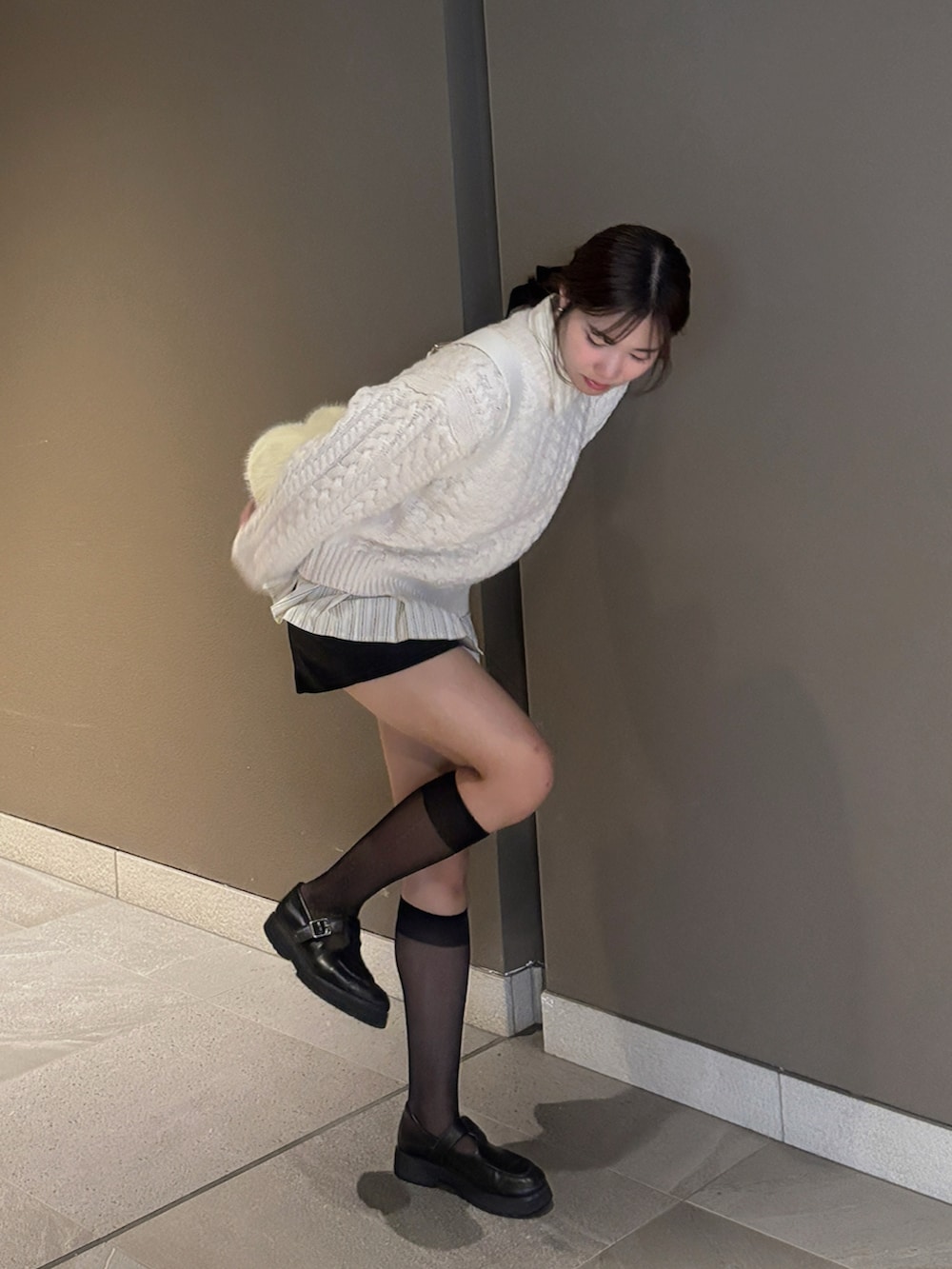 ホワイト系のニット/セーター、ベージュ系のシャツ/ブラウス、イエロー系のショルダーバッグを着用したレディースの秋コーディネートの2枚目の写真