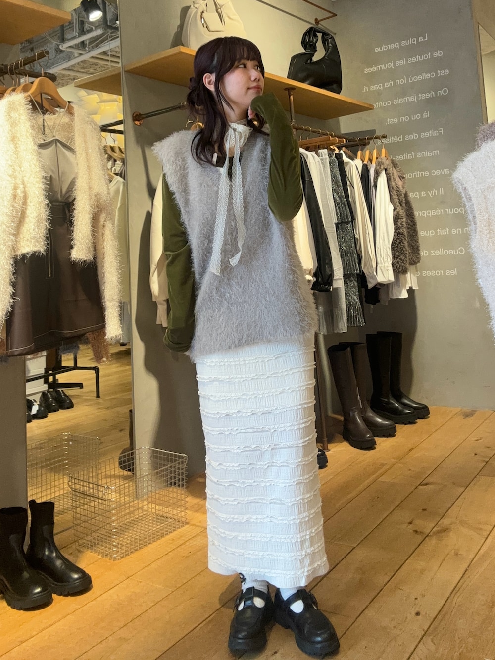 ブラック系のローファー、グレー系のベスト、ホワイト系のスカートを着用したレディースの冬コーディネートの2枚目の写真