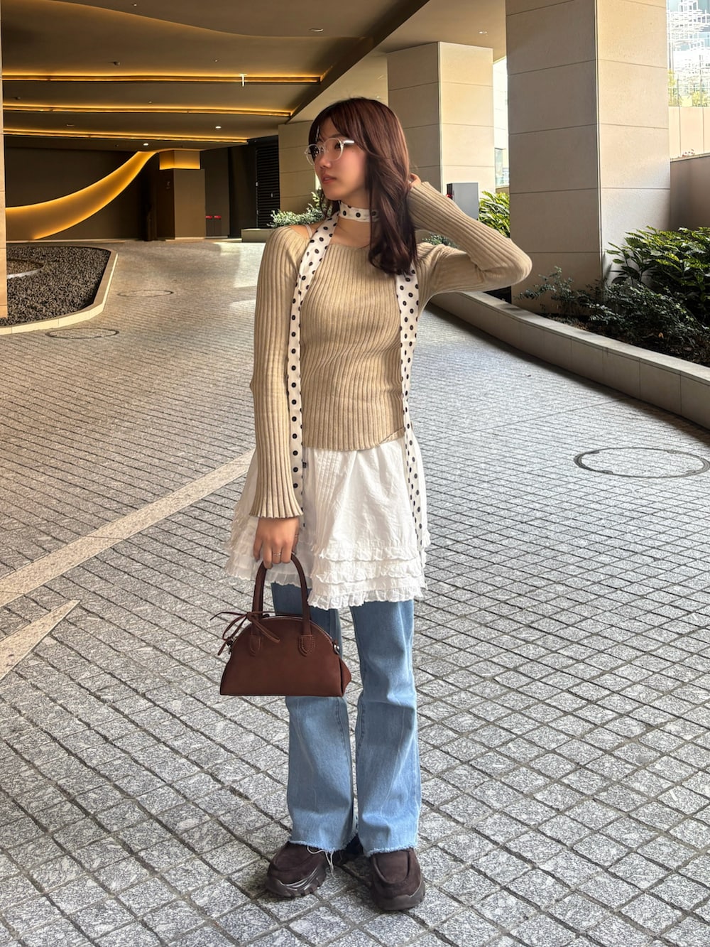 ブラウン系のハンドバッグ、ブラウン系のローファー、ブルー系のデニムパンツを着用したレディースの冬コーディネートの2枚目の写真