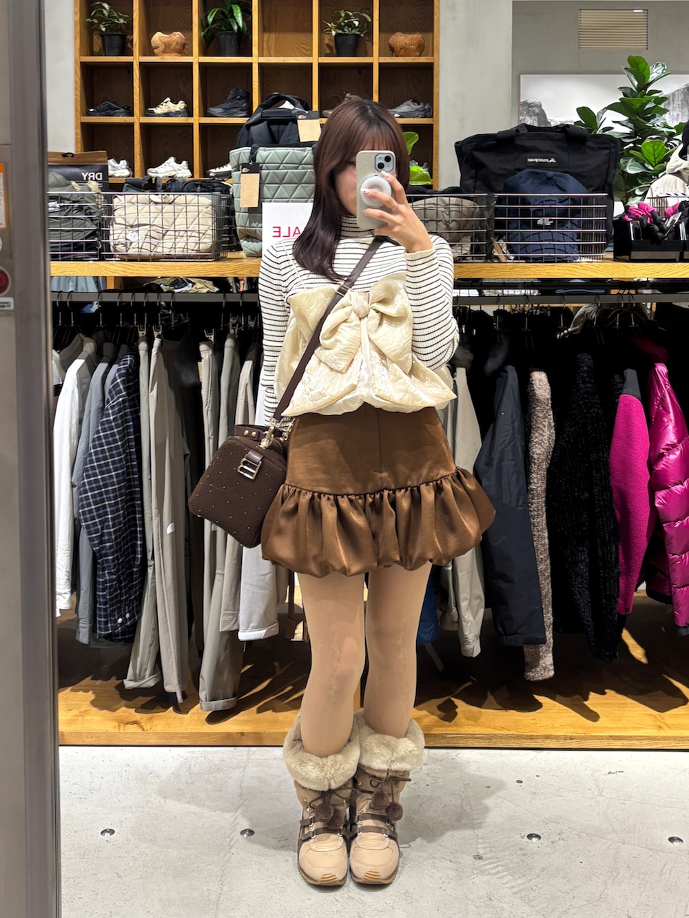 ブラウン系のブーツ、ブラウン系のスカート、ホワイト系のその他アウターを着用したレディースの冬コーディネートの2枚目の写真