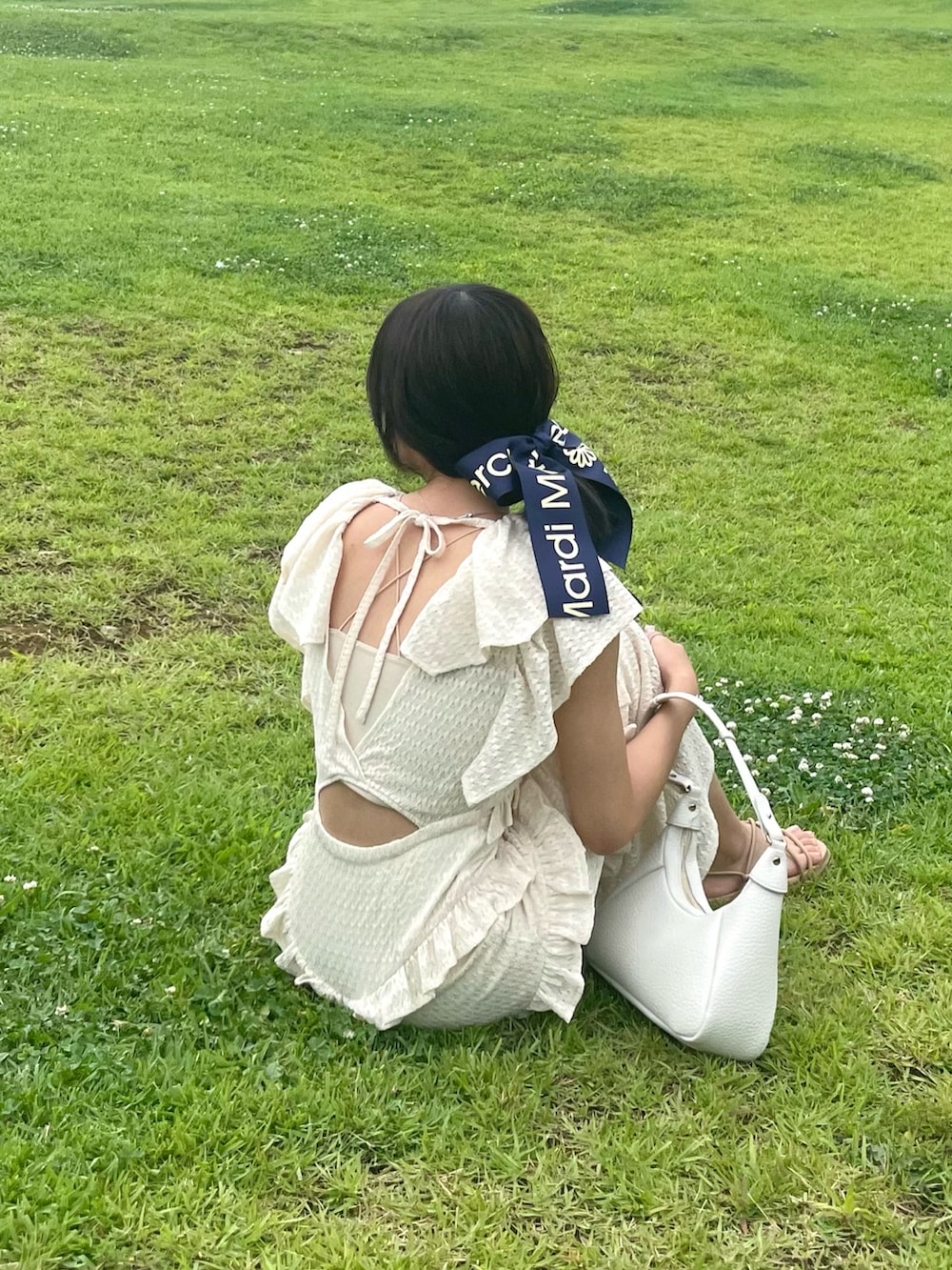 イエロー系のワンピース、ホワイト系のハンドバッグ、ベージュ系のサンダルを着用したレディースの夏コーディネートの3枚目の写真