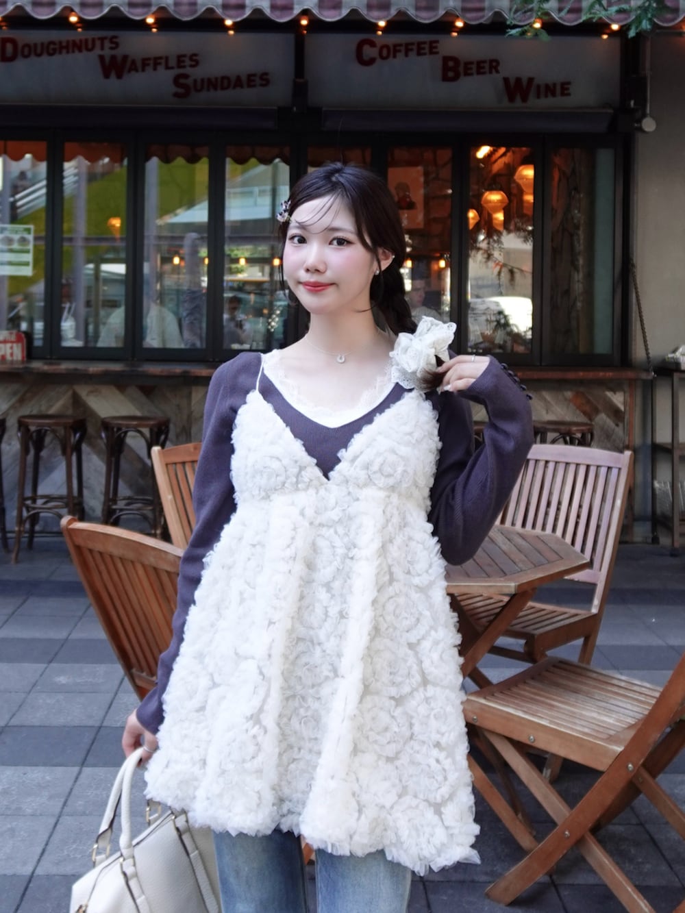 ベージュ系のテーラードジャケット、ブルー系のデニムパンツ、ホワイト系のドレスを着用したレディースの秋コーディネートの3枚目の写真